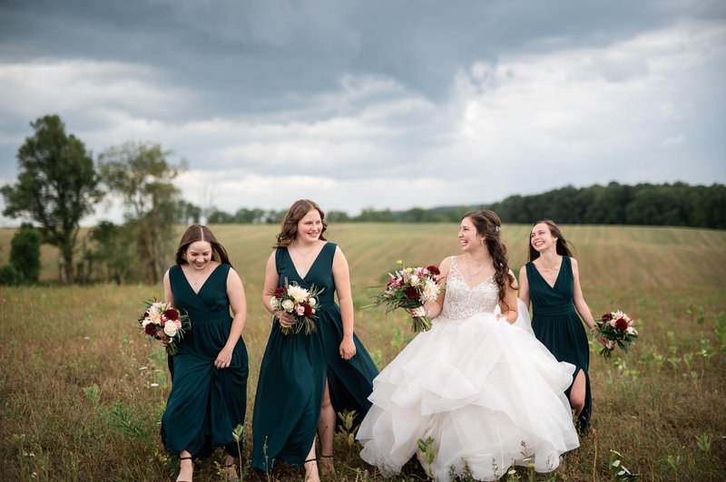 Bride laughing with bridesmaids in a field