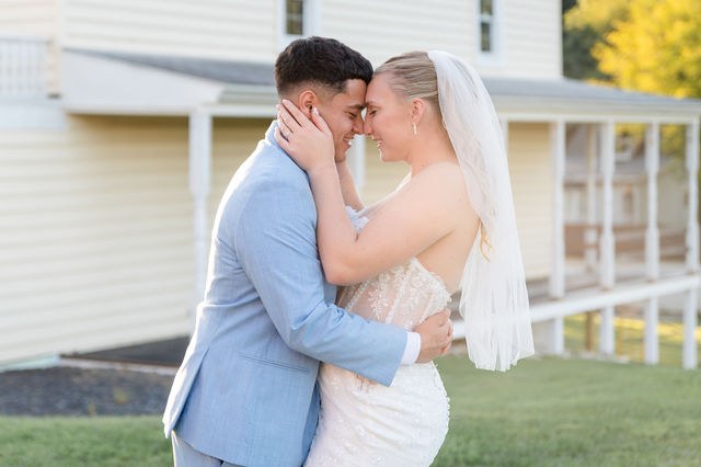 Bride and groom embracing outside a white building