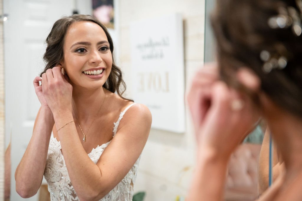 Bride putting on earrings in front of a mirror
