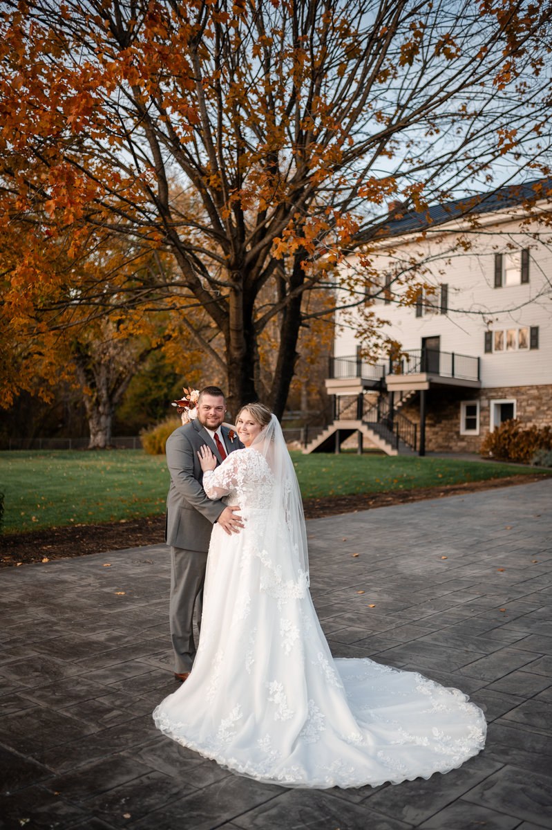 Couple beneath an autumn tree outside a historic building
