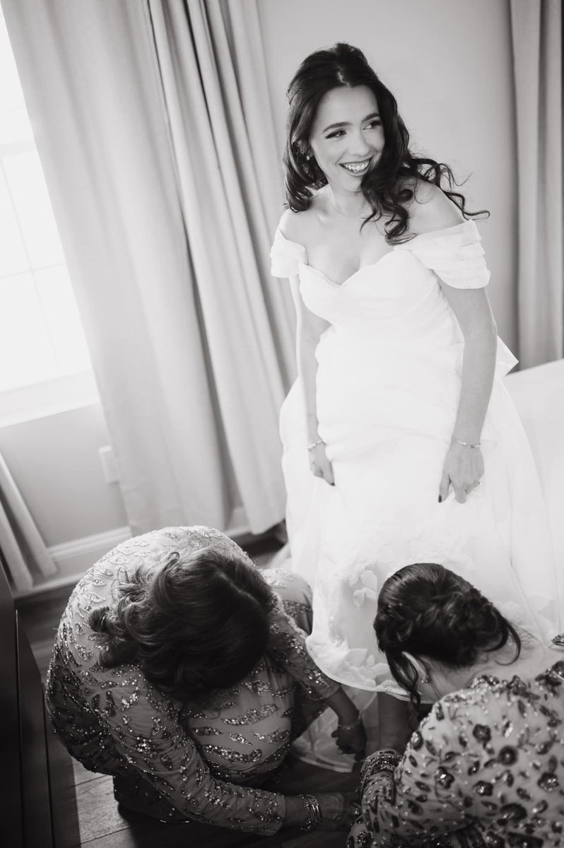 Loved ones adjusting the bride’s wedding gown