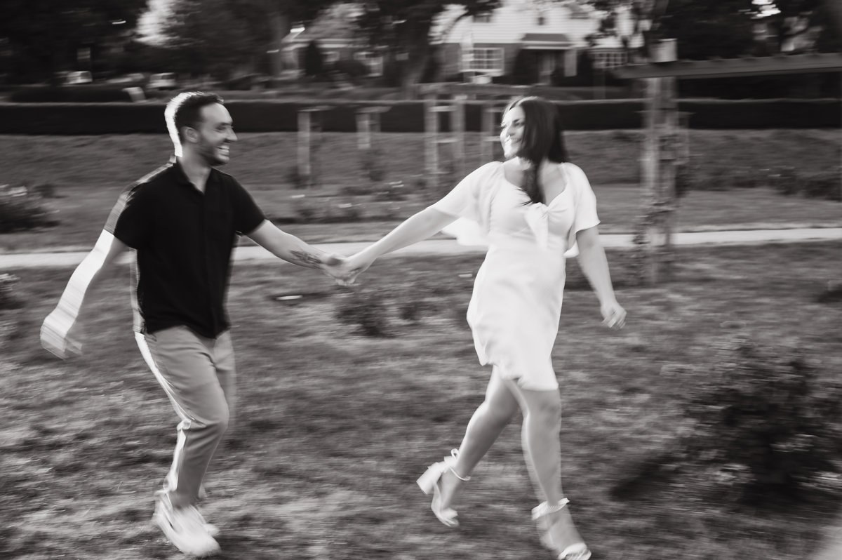 Black and white portrait of newlyweds running hand in hand