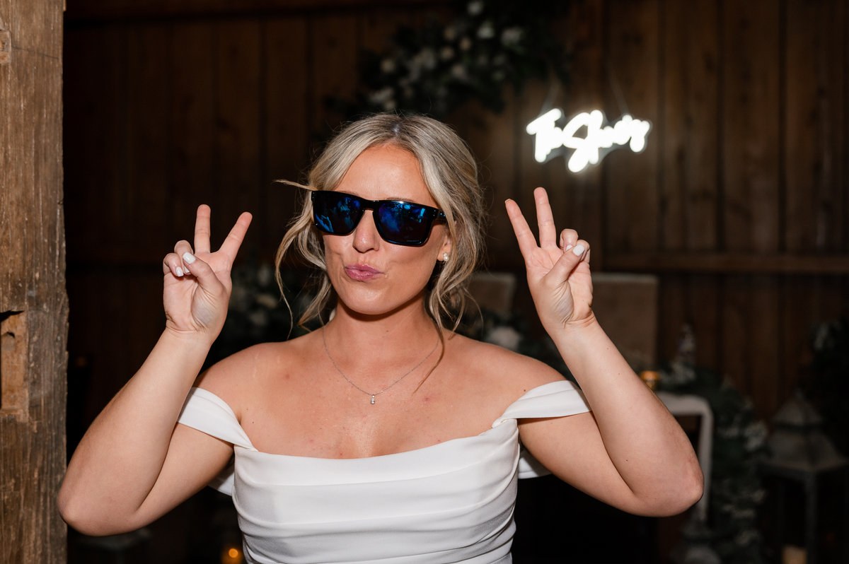 Bride wearing sunglasses and celebrating at the reception